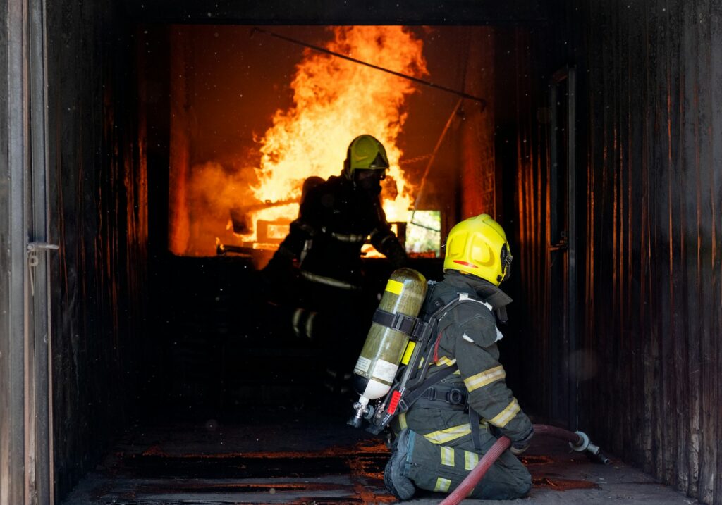 TTwo firefighters of fireman try to extinguish the fire in container during the practice